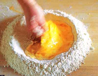 Gradually mix the eggs into the flour with the fingers of one hand