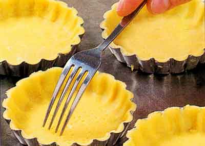 Set the tartlet tins on the baking sheet and prick the dough with the fork.